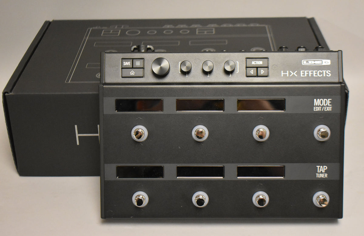 A dark gray multi-effects pedal with six footswitches, six small screens, and four control knobs, shown with its black box.