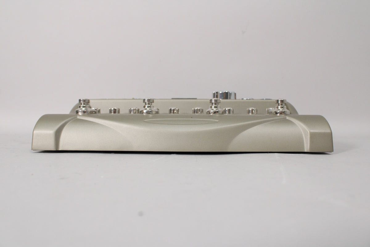 The silver-grey pedal is viewed from the front, showing its curved base and the row of six silver footswitches along the top.