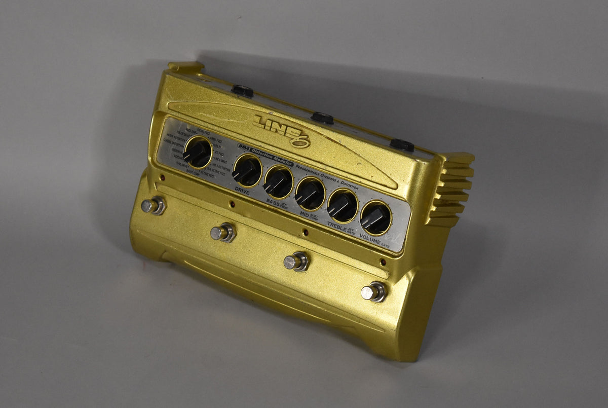 A gold distortion pedal, angled from the front right, with five black control knobs and four silver footswitches.