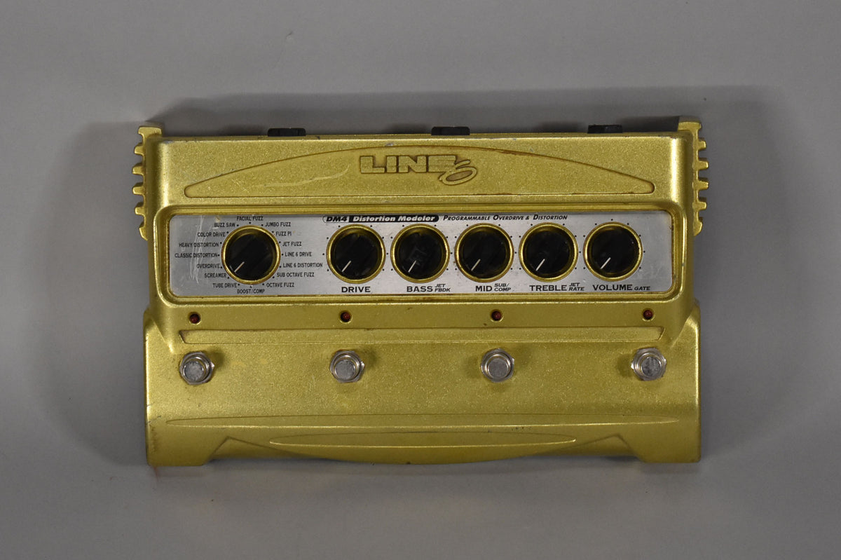 Gold-colored pedal, top-down view, with six black control knobs and four silver footswitches, showing some scuffs and wear.