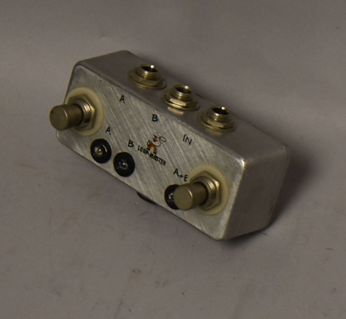 A brushed metal "LOOP-MASTER" pedal with multiple jacks and switches, labeled A, B, IN, and A+B.