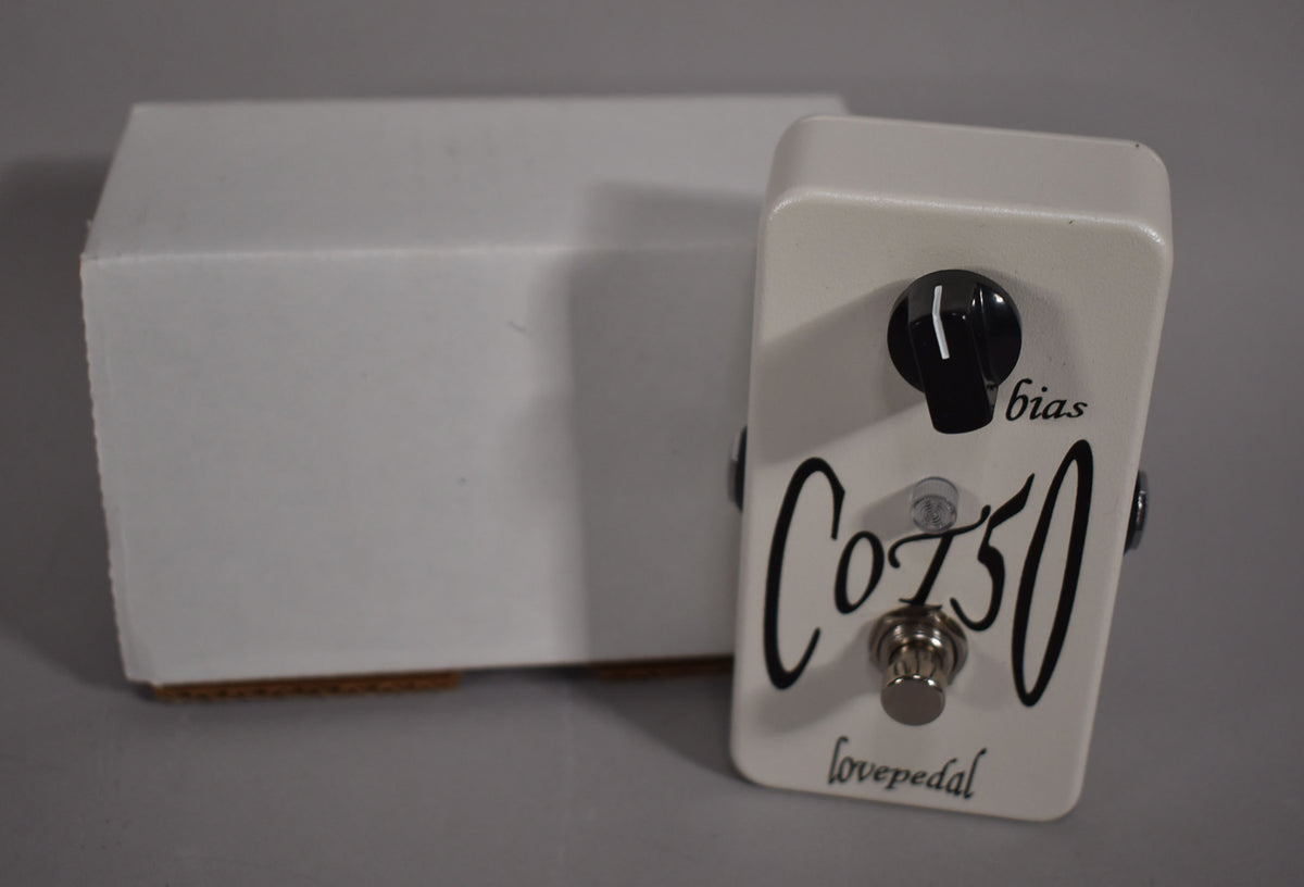 Off-white pedal with a single black "bias" knob and a chrome footswitch, next to a plain white box.