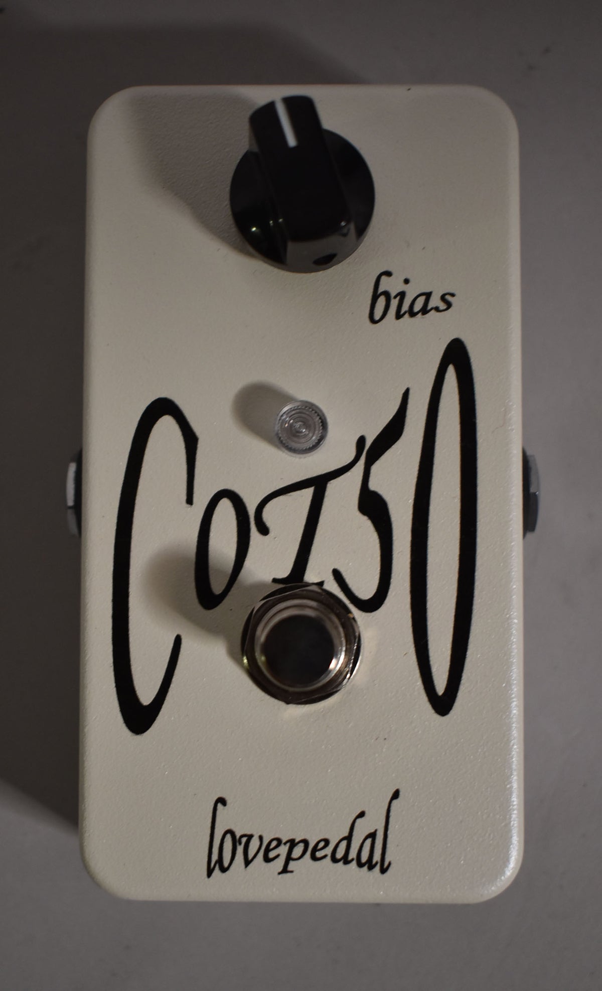 Cream-colored guitar pedal with a single black knob at the top, a small silver LED, and a chrome footswitch at the bottom.