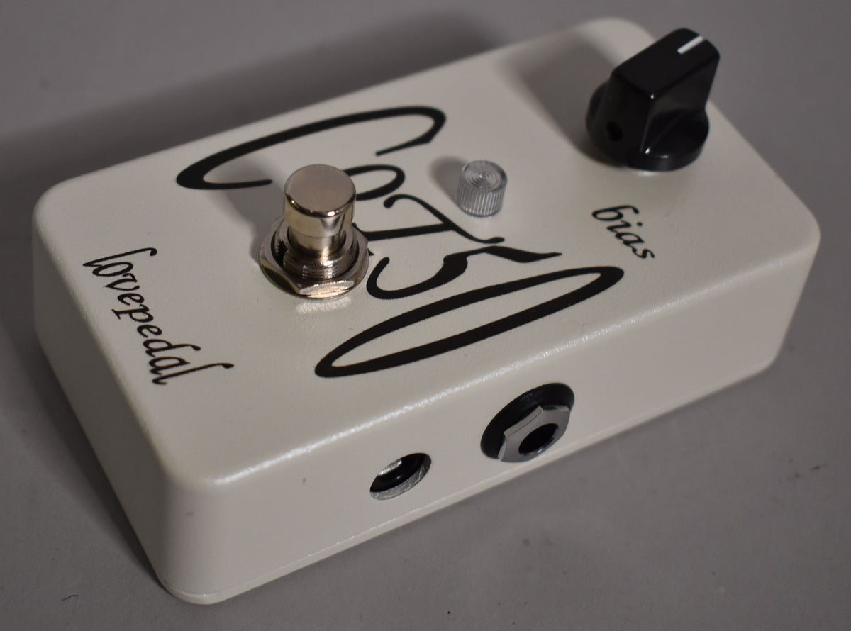 Off-white pedal with a chrome footswitch, a small silver knob, and a black chicken head knob, viewed from the front-right.