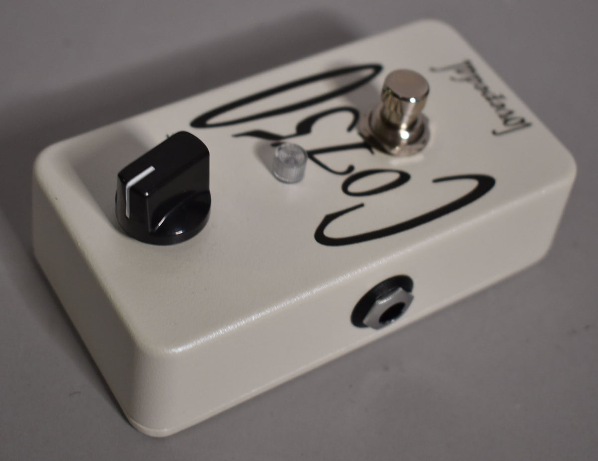 Off-white pedal with a single black control knob, a chrome toggle switch, and a visible input jack on the right side.