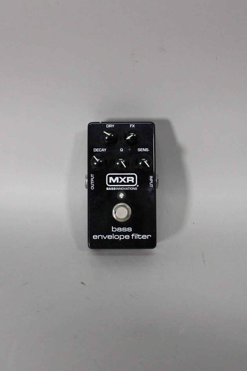 A black rectangular pedal with six small black control knobs, a silver footswitch, and a small white LED, viewed from above.