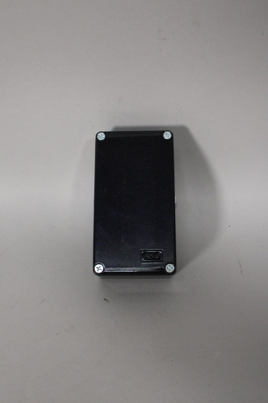 The pedal's black bottom plate is secured by four silver Phillips head screws, with a small recessed label near the bottom.