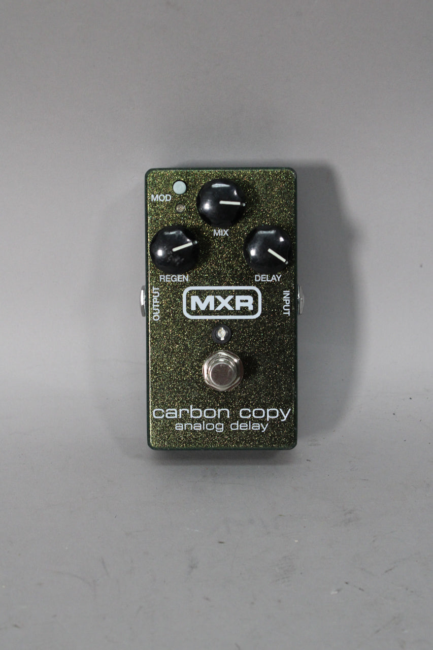A dark green glitter-finish guitar pedal with three black control knobs, a small LED, and a silver footswitch, viewed from above.