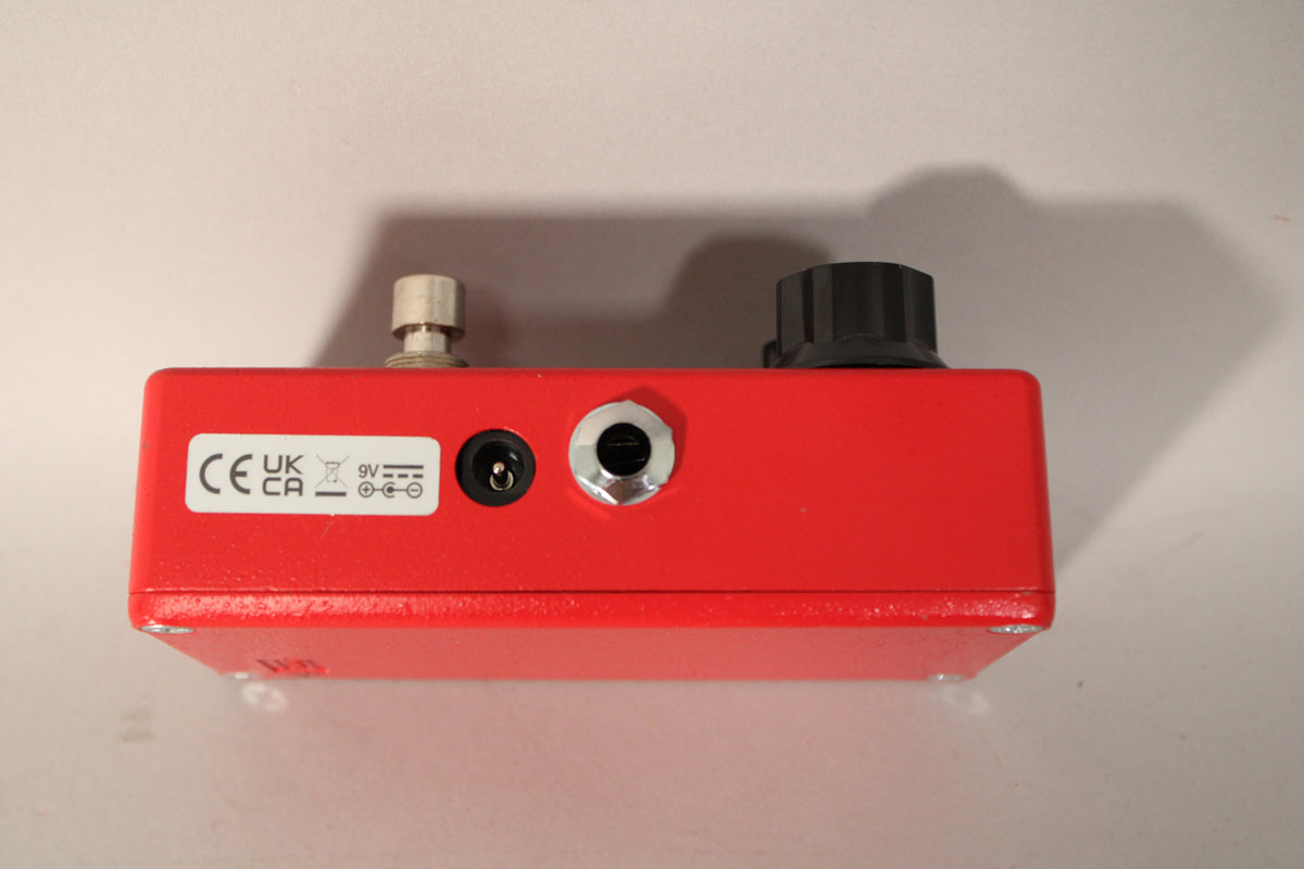Top-down view of the red pedal, showing the DC input, a 1/4" jack, and a black knob on the right, with minor paint chips.