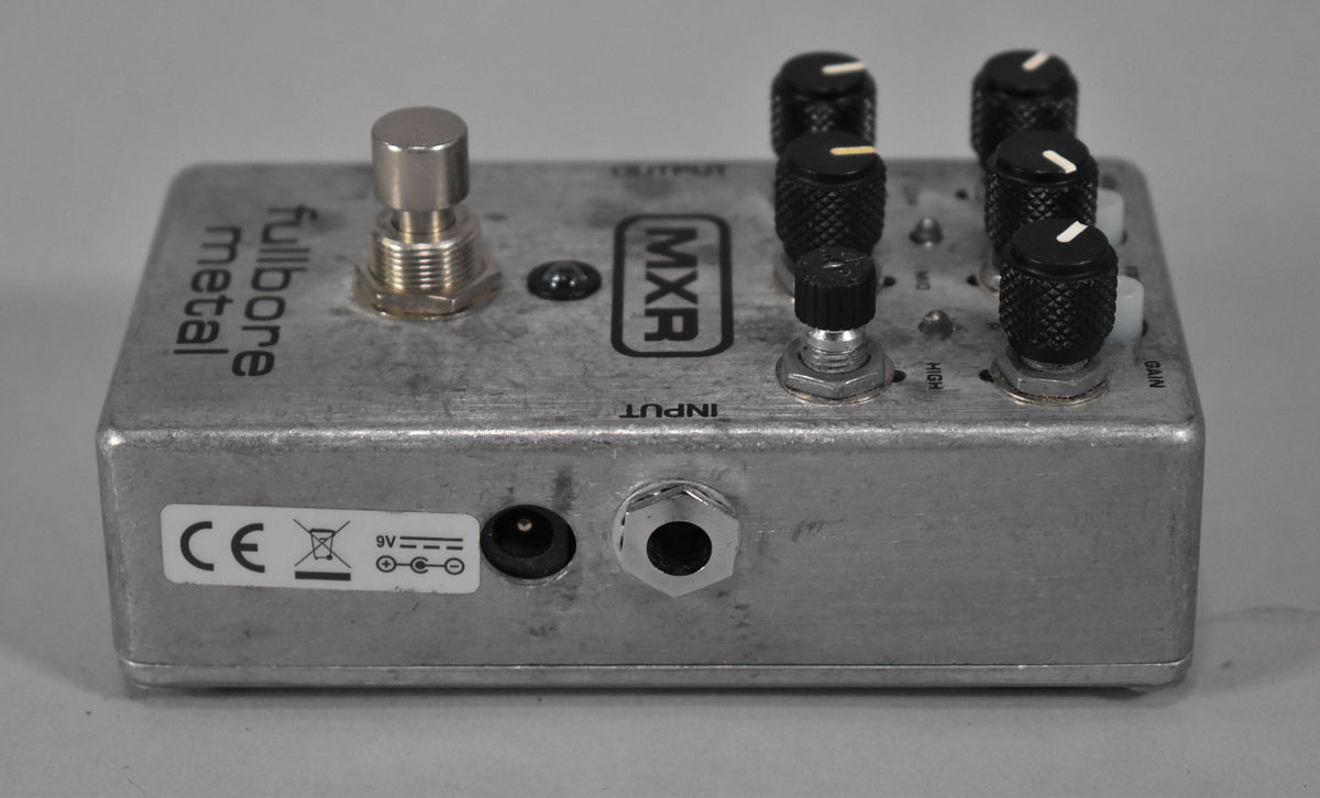 The silver pedal is angled from the left, showing the input jack, power port, and a sticker on its side.