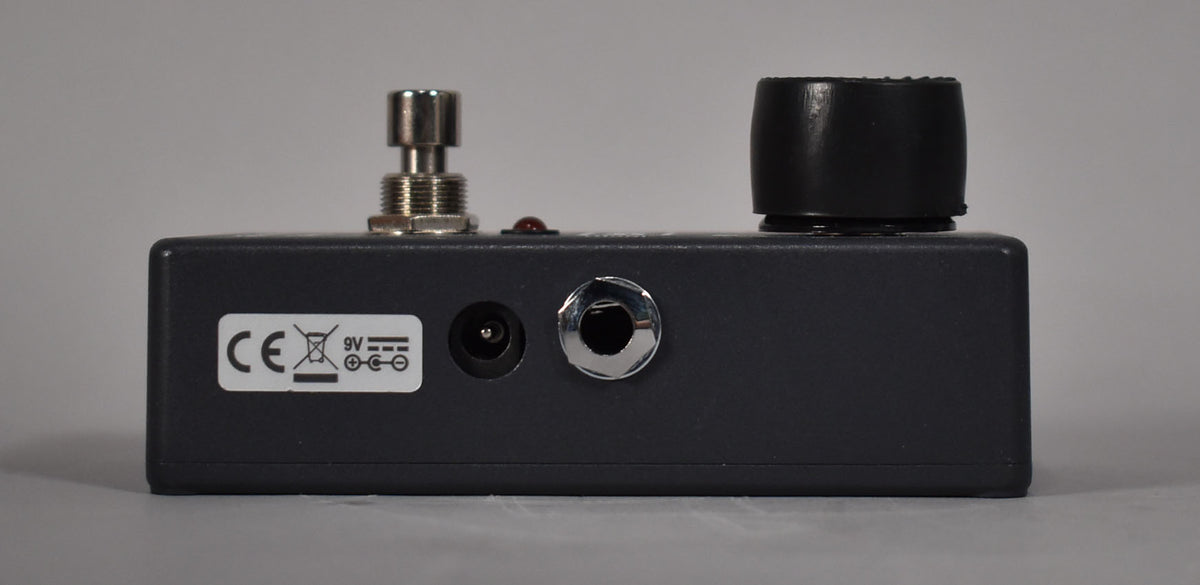The dark grey pedal is viewed from the back, showing a chrome input jack, a power input, and a white CE sticker.