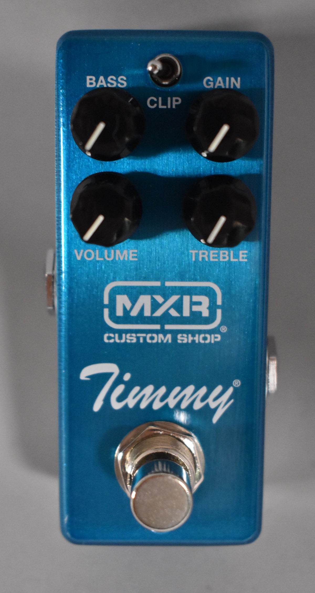 Overhead view of a metallic blue pedal with four black knobs, a silver footswitch, and a small silver toggle switch.