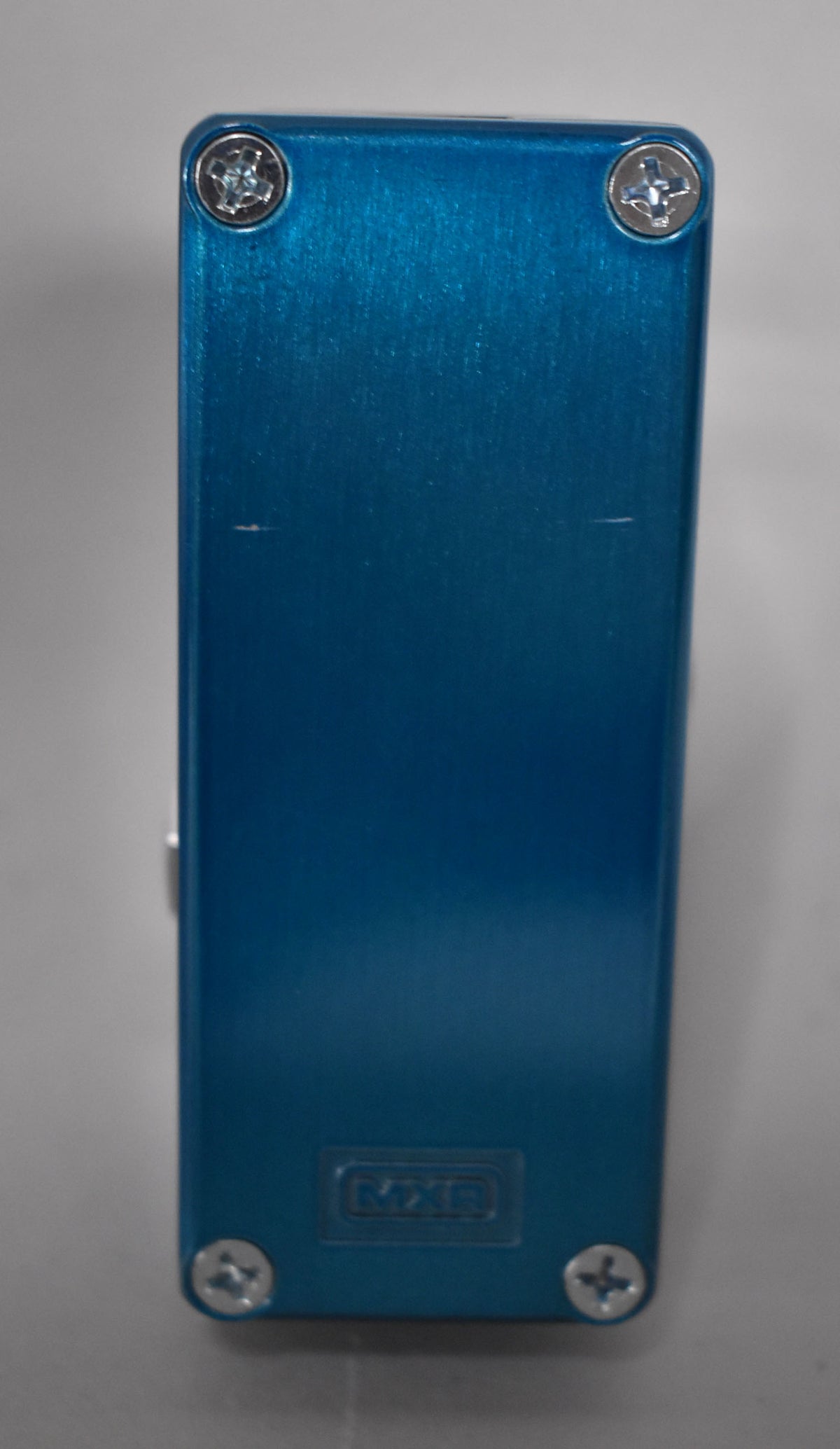 The top of the mini pedal is a brushed metallic blue with four silver Phillips head screws and a few light scratches.