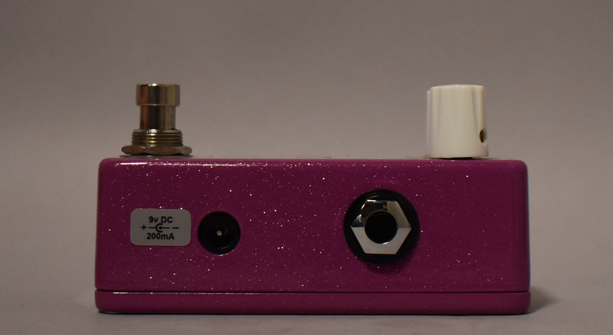 The Malekko Omicron Phaser is shown from the back, revealing its glittery purple finish, a power input, and a single white knob.