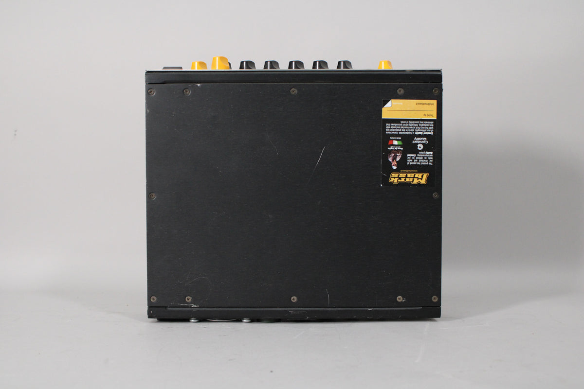 The black amp head is viewed from the left side, showing a few yellow knobs on top and a sticker on the right side.