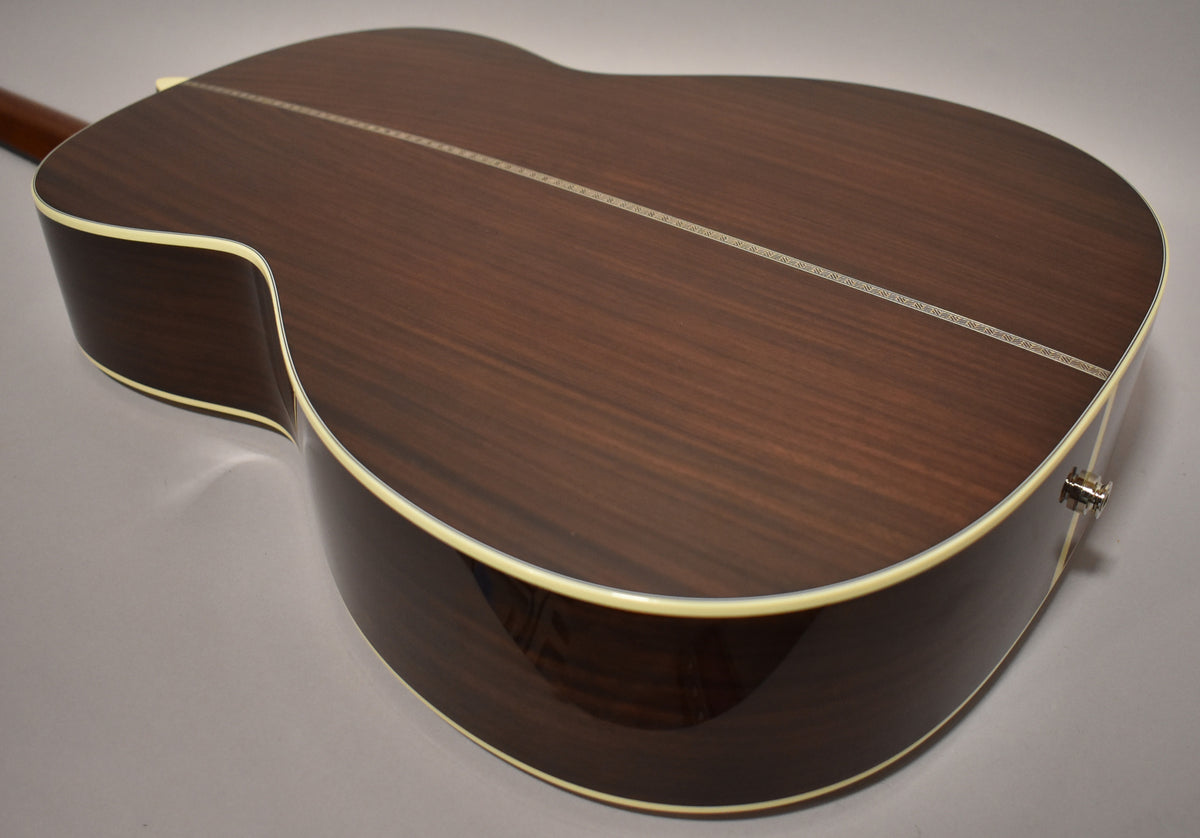 The guitar's dark brown back and sides, with a subtle wood grain, are visible from the upper bout to the lower bout.