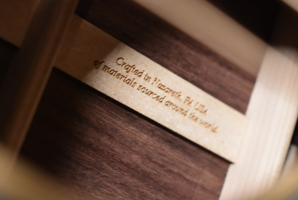 Close-up of the guitar's interior, showing a light wood brace with "Crafted in Nazareth, PA USA of materials sourced around the world" engraved.