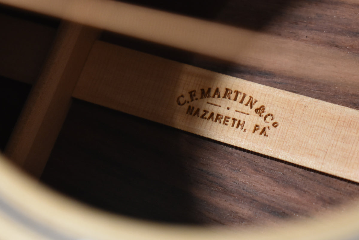 An interior view of the guitar's soundhole, showing the light-colored wooden bracing and dark wood grain of the back.