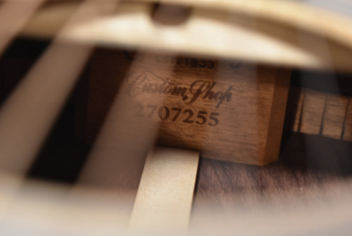 A blurry, close-up view inside the soundhole, showing the light brown wood interior with dark stamped text.
