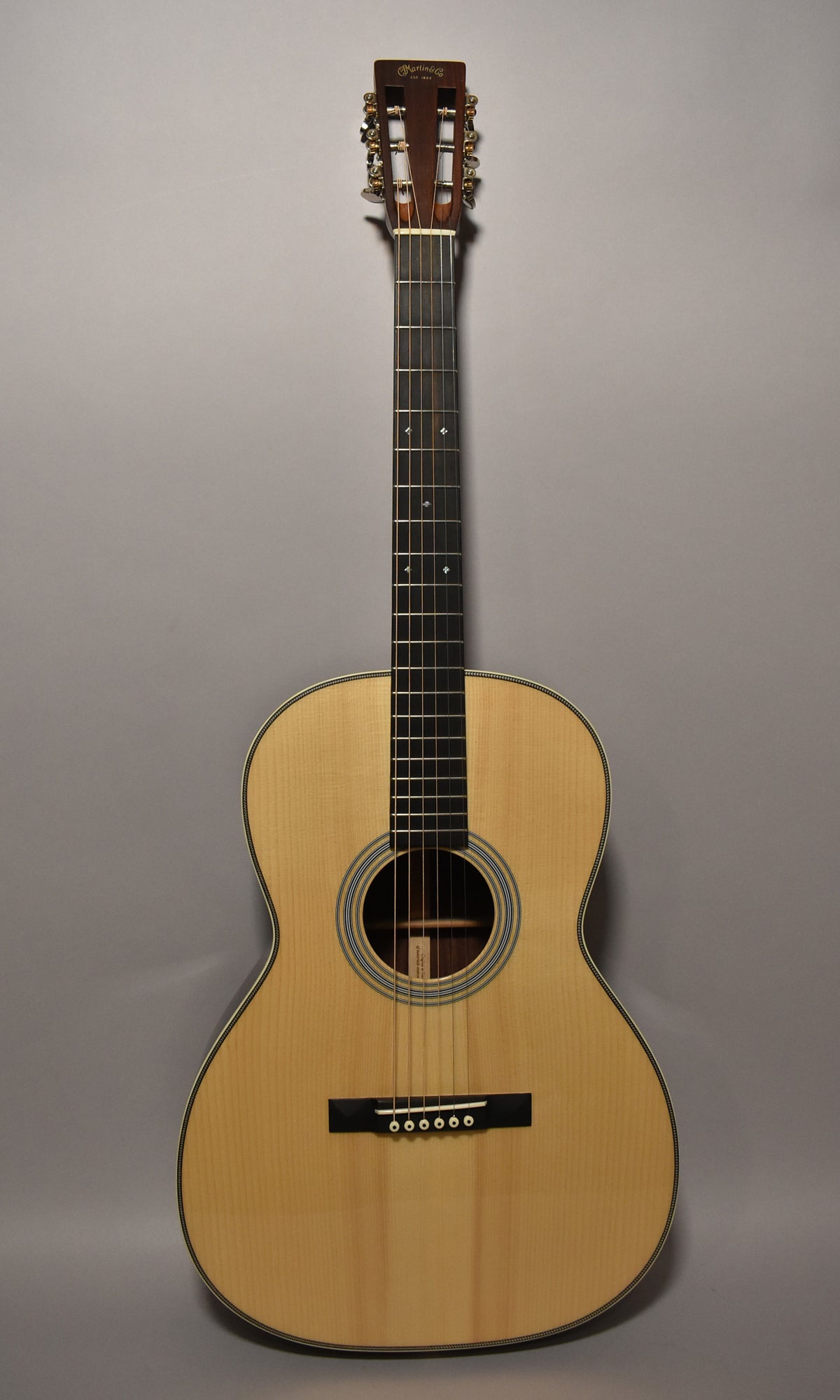 Full-front view of a natural finish acoustic guitar with a slotted headstock, gold tuners, and a dark fingerboard with diamond inlays.