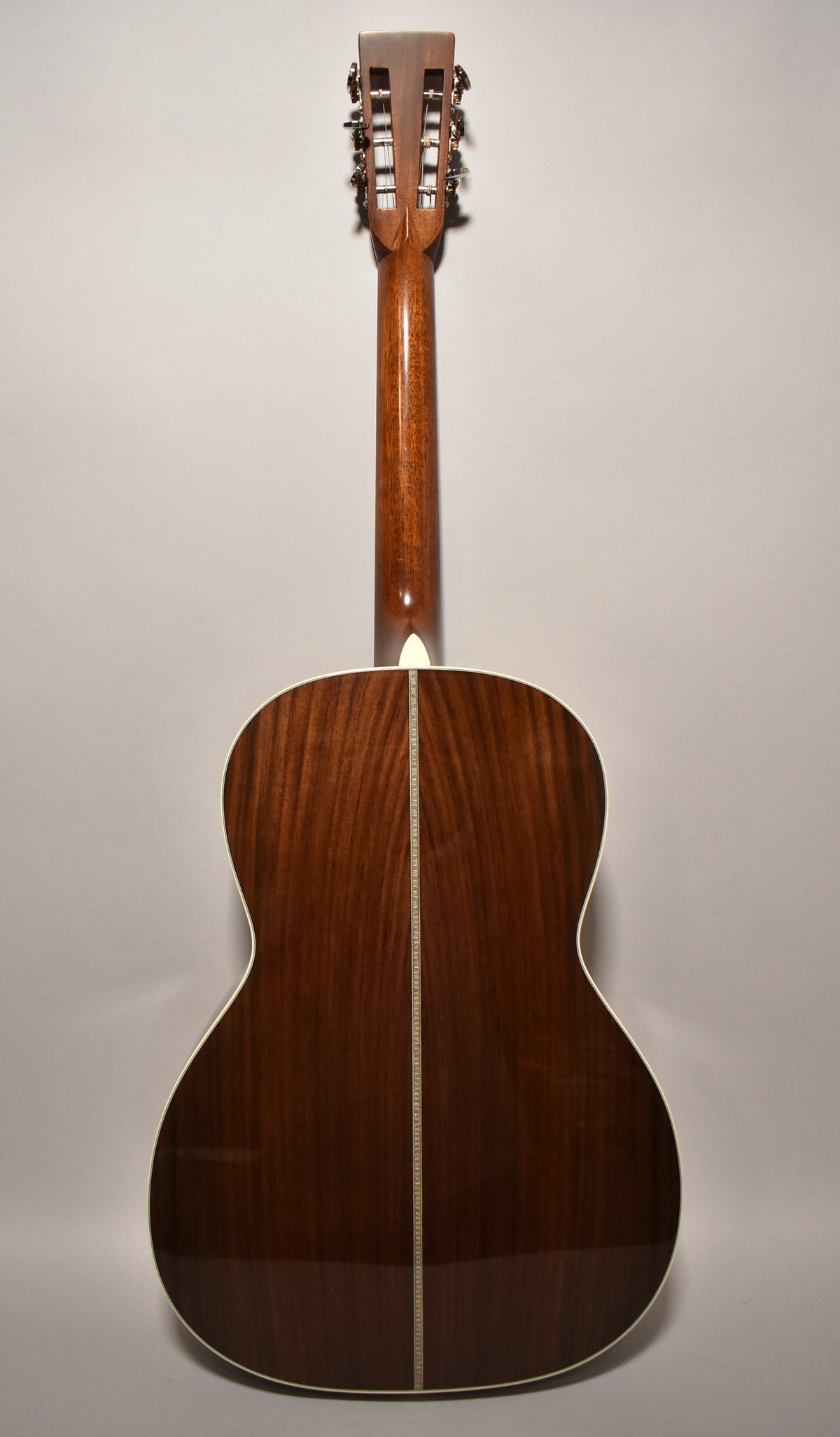 Full rear view of a glossy dark brown acoustic guitar with a light-colored binding and a decorative backstrip.
