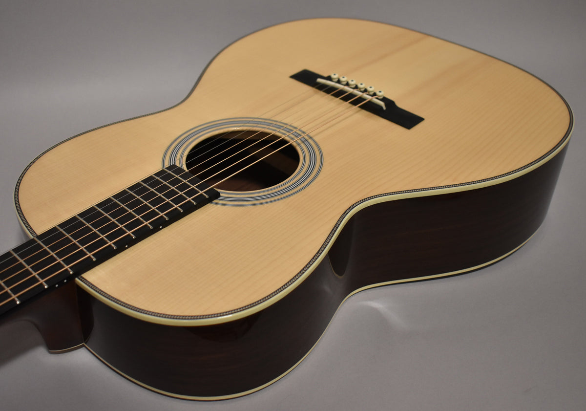 The acoustic guitar's light natural top and dark sides are angled from the lower left, showing the fretboard, soundhole, and bridge.