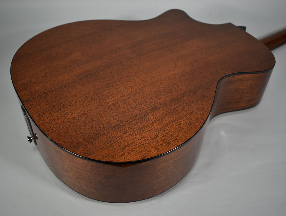 The acoustic guitar's dark brown back and cutaway side are angled from above, showing a chrome endpin jack.