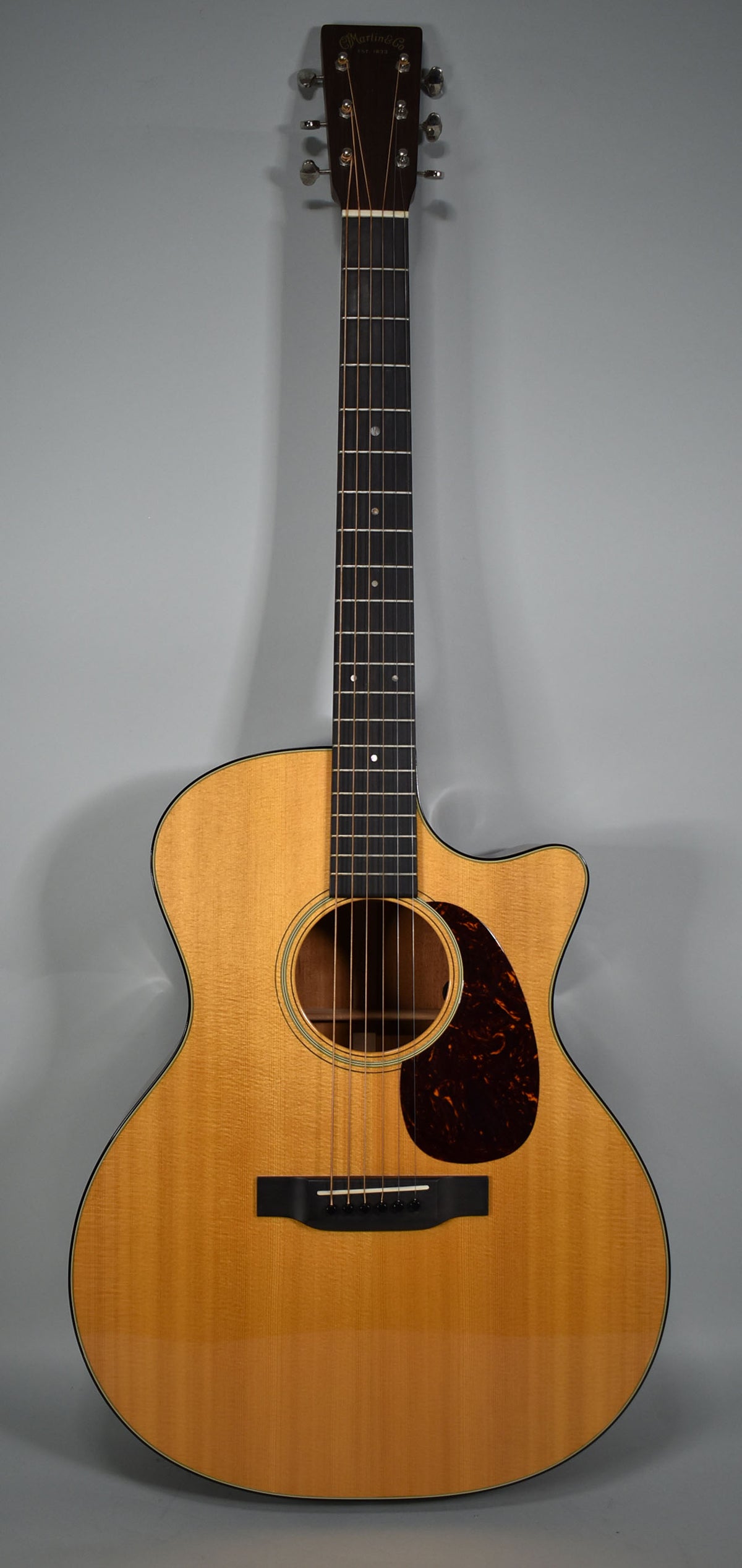 Full-front view of a light-wood acoustic guitar with a cutaway body, dark pickguard, and black bridge, showing minimal wear.