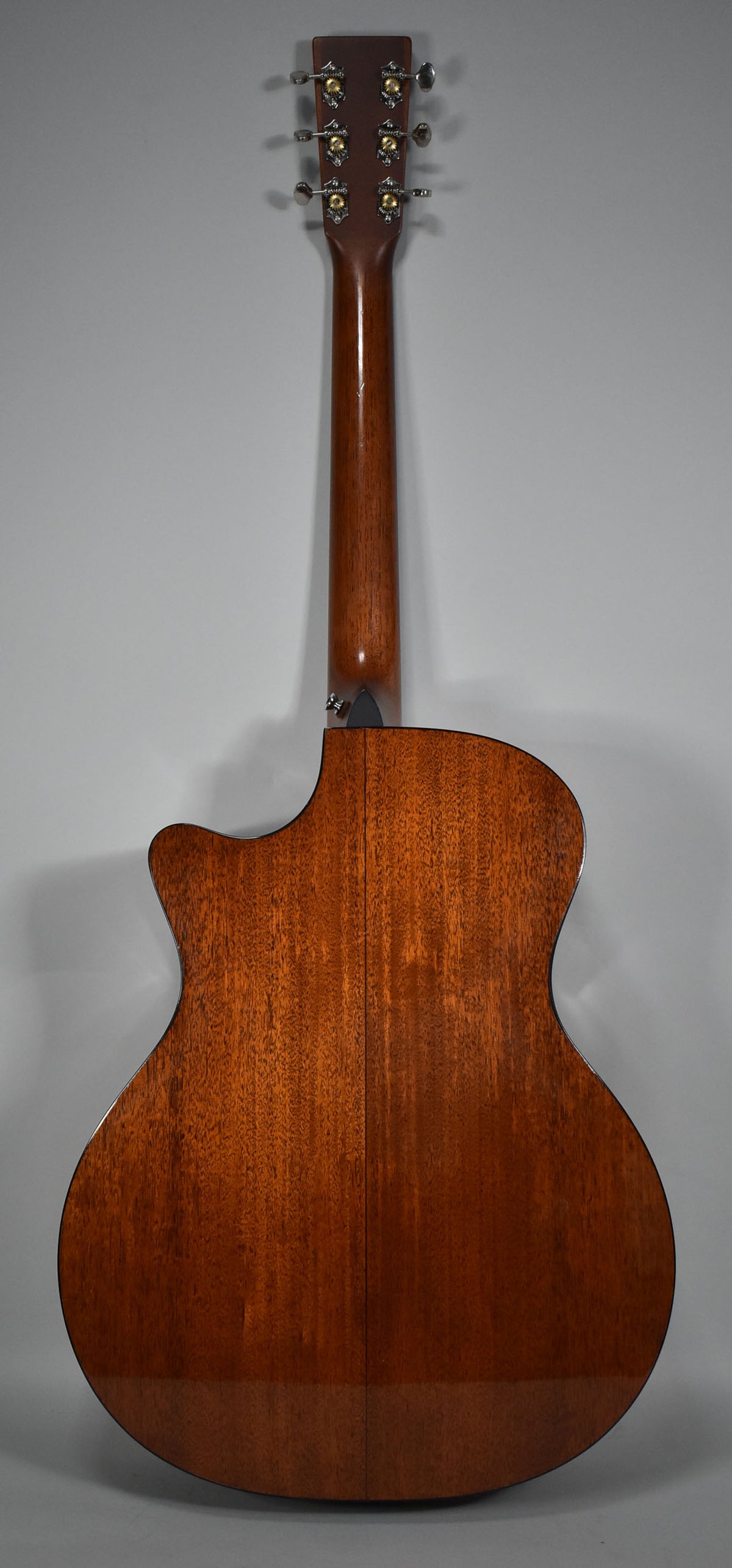 The guitar's back and neck are shown, featuring a rich, reddish-brown wood grain, a cutaway, and six silver and gold tuners.