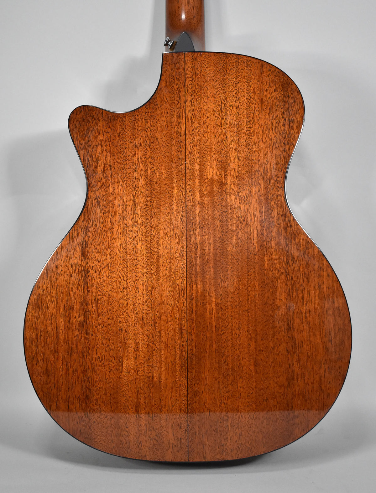 The guitar's glossy reddish-brown back, with a visible seam down the center, shows a cutaway on the upper left.
