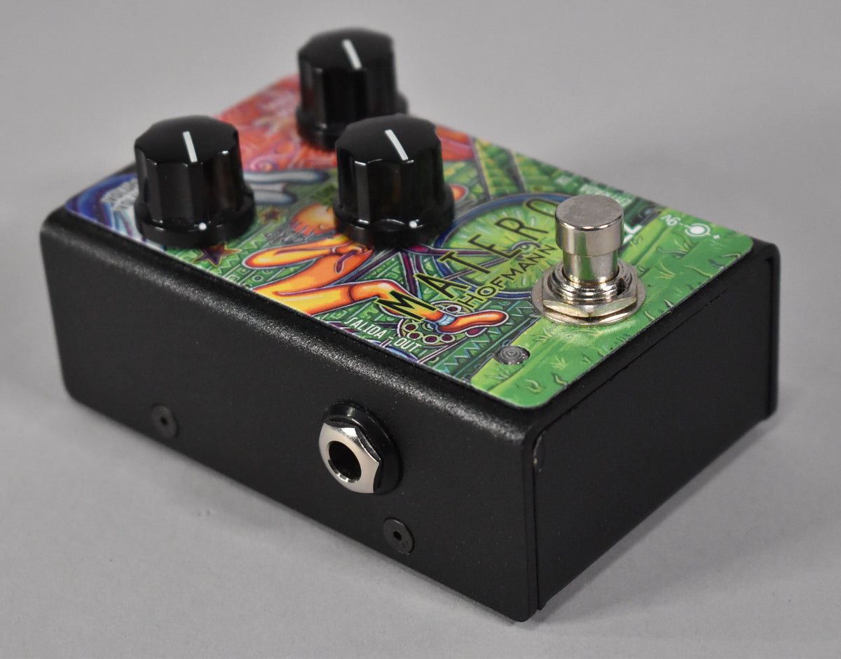 The black pedal, angled from the left, has a colorful, psychedelic top with three black knobs and a silver footswitch.
