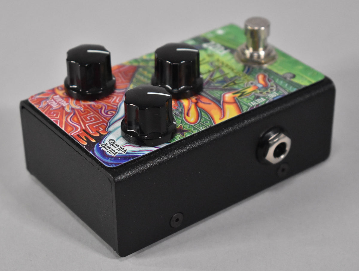The black fuzz pedal is angled to show its right side and top, featuring three black knobs and a colorful, intricate graphic.