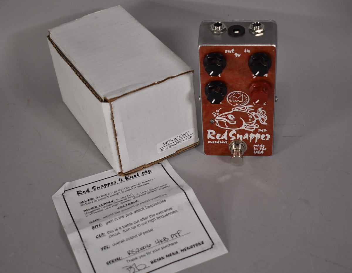 The red pedal with a fish graphic and four black knobs is angled beside its white box and instruction sheet.