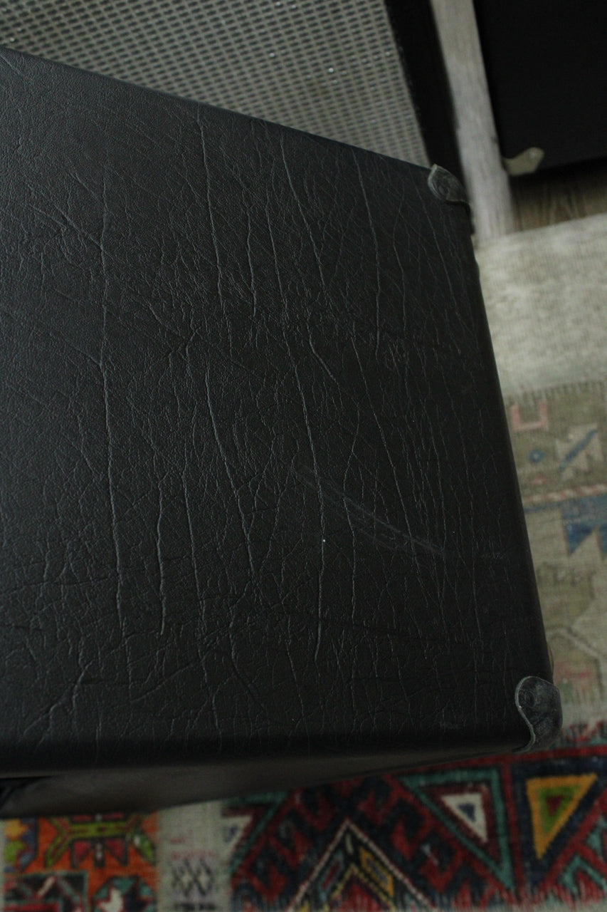 Close-up of the amp's black textured tolex covering, showing some scuffs and a metal corner protector on the top right.