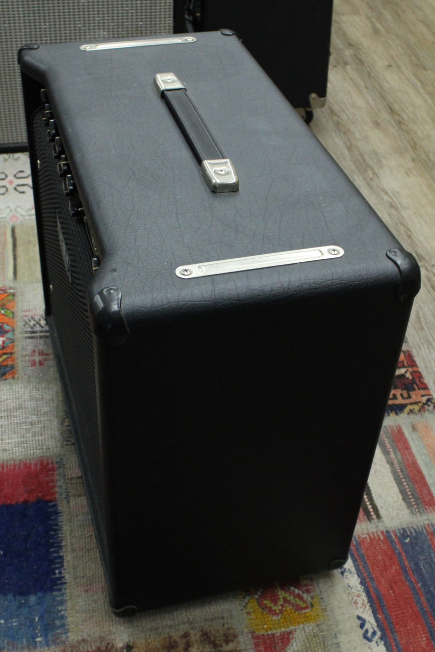 Top-down view of the black textured amp, showing its silver-capped rubber handle, two long silver vents, and four black corner protectors.