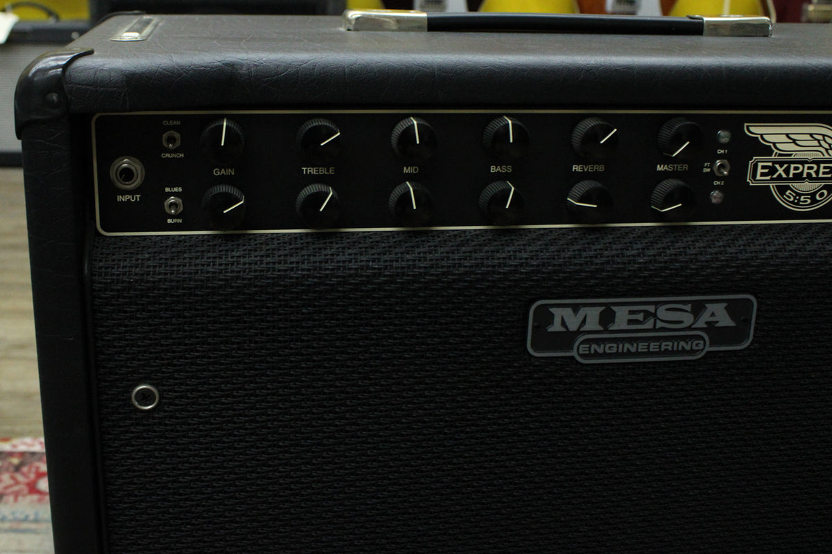 Close-up of the black tolex amp's control panel, showing 8 black chicken head knobs, an input jack, and channel switches.