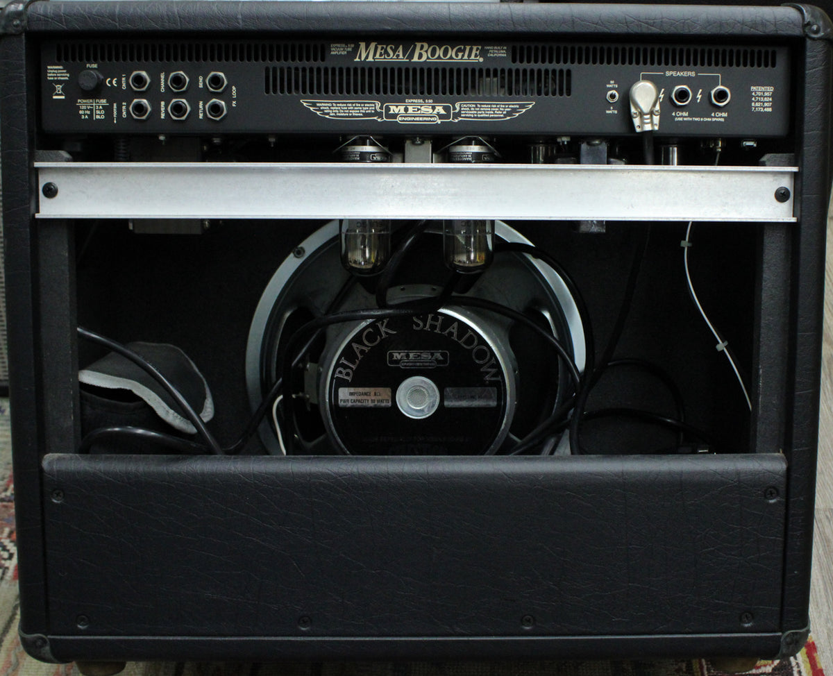 Rear view of the black tolex amp, showing the speaker, four glowing tubes, and various input/output jacks.