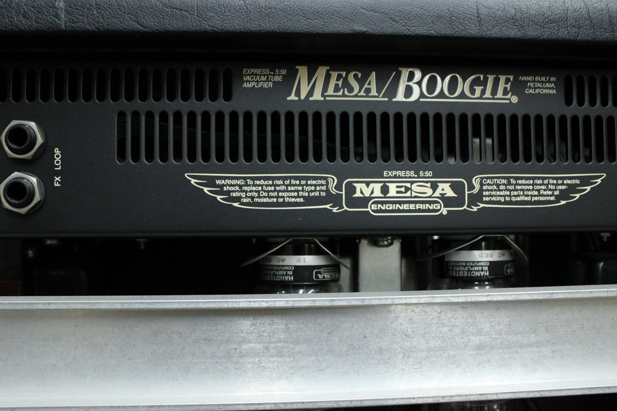 Close-up of the amp's black metal rear panel, showing two FX Loop jacks, ventilation slots, and two glowing vacuum tubes below.
