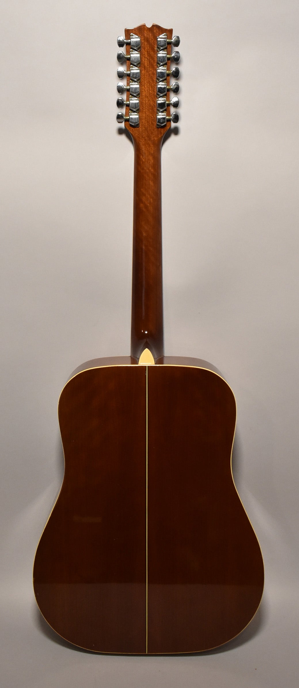 The guitar's back is dark brown with a glossy finish, a light center seam, and a light binding around the edges.