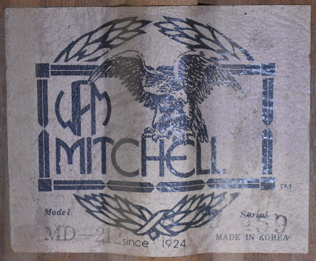 Close-up of the guitar's internal label, showing a black eagle logo, "MD-212" model, and "MADE IN KOREA" on aged paper.