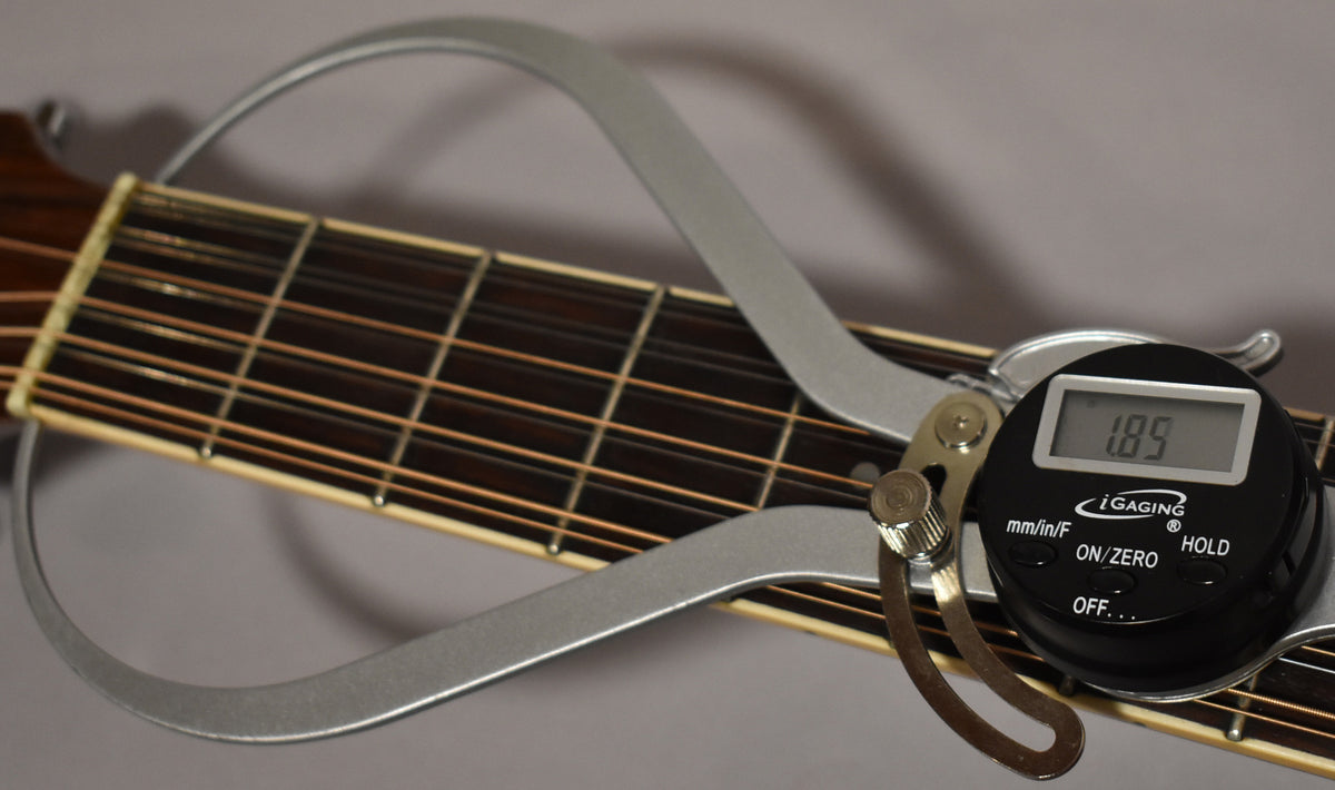 A digital caliper measures the 12-string guitar's dark fretboard and light binding, showing a 1.89mm reading.