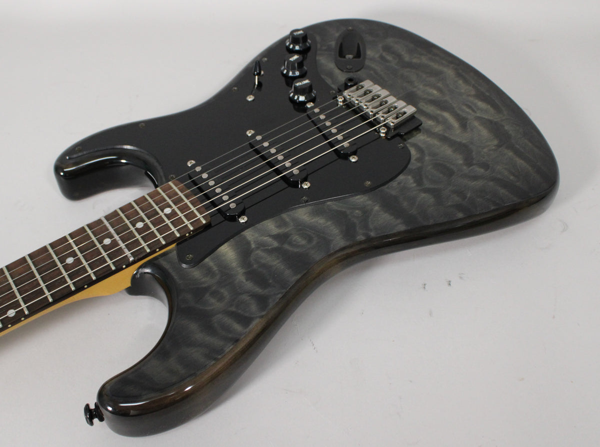 The electric guitar's upper body and neck are visible, showing a grey flamed maple top, black pickguard, and three black single-coil pickups.