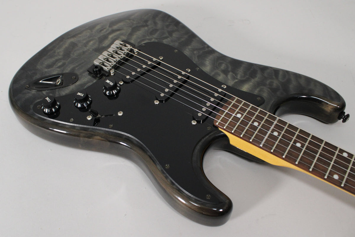 The electric guitar's upper body, in a glossy gray wood grain, features a black pickguard, three black knobs, and a rosewood fretboard.