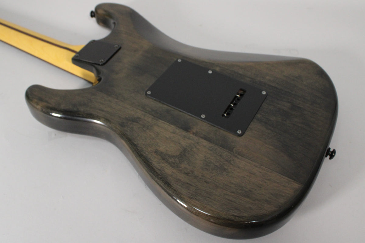 The back of a dark gray electric guitar, showing its glossy wood grain, black tremolo cover, and light-colored neck.