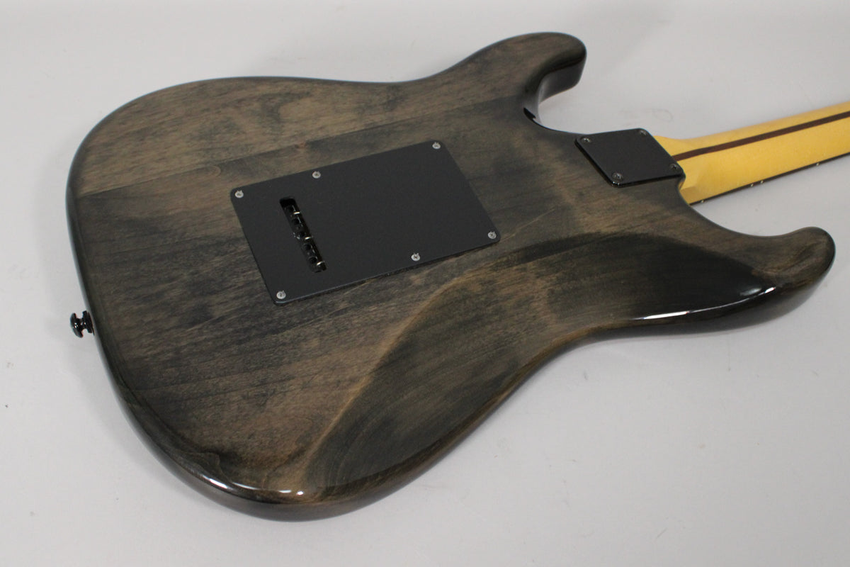 The back of a gray-stained guitar body with a gloss finish, showing black control and tremolo covers, and a light-colored neck.