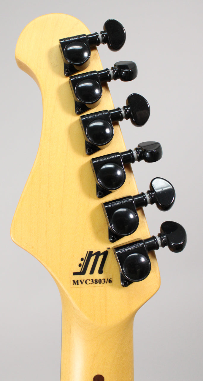 The back of a light wood guitar headstock with six black tuning machines, angled slightly from the left.