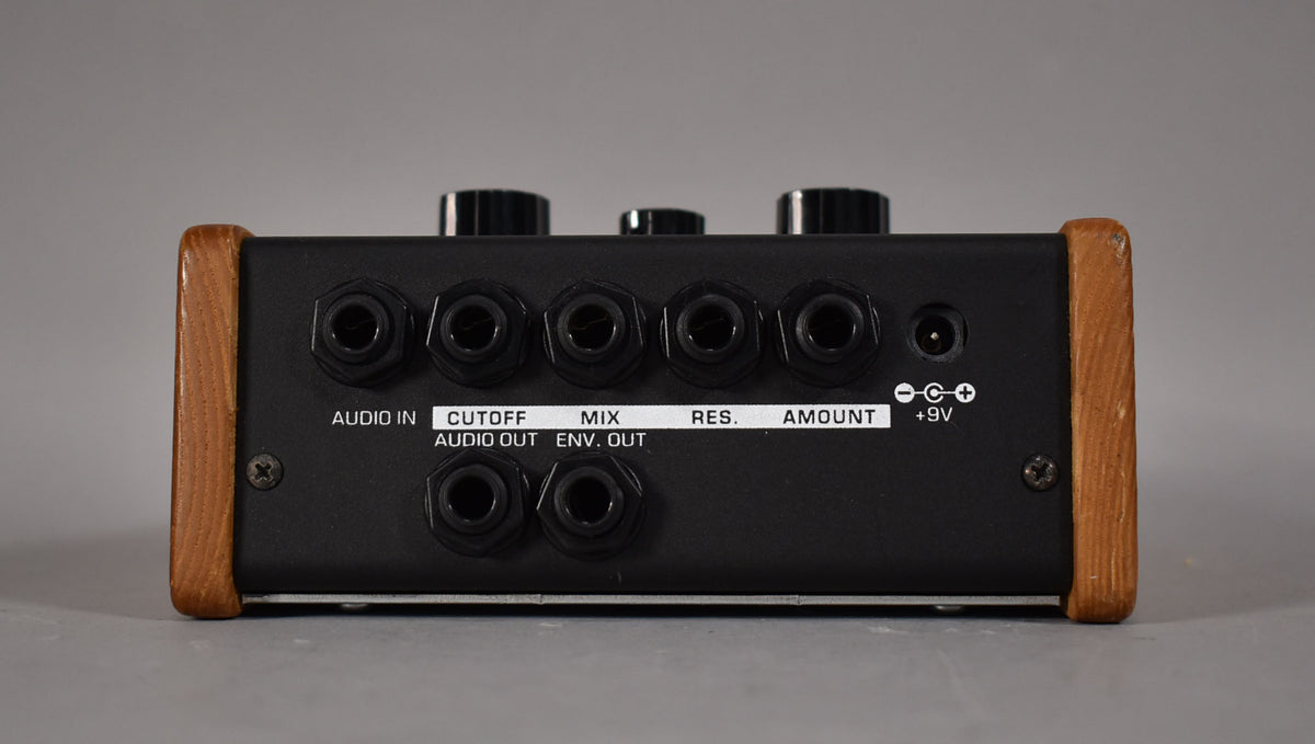 The rear of the black pedal shows eight 1/4" jacks, a power input, and light wood side panels with minor wear.