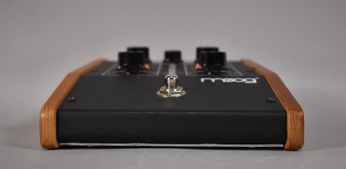 A Moog MF-101 Moogerfooger Lowpass-Filter pedal, seen from the front, with a toggle switch and three knobs visible.