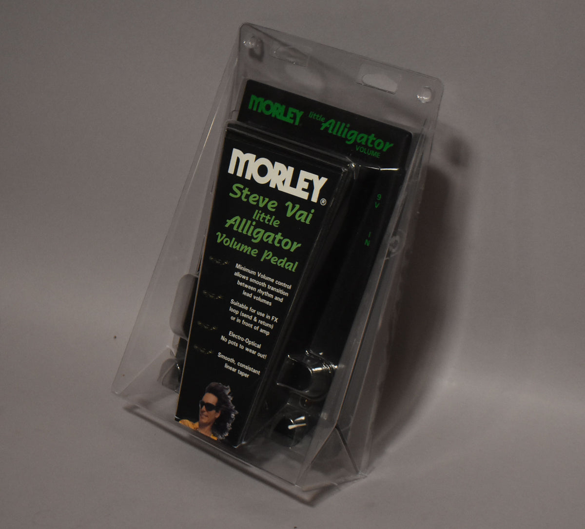 The volume pedal is sealed in clear plastic blister packaging, angled to show the black pedal and green-lettered card.