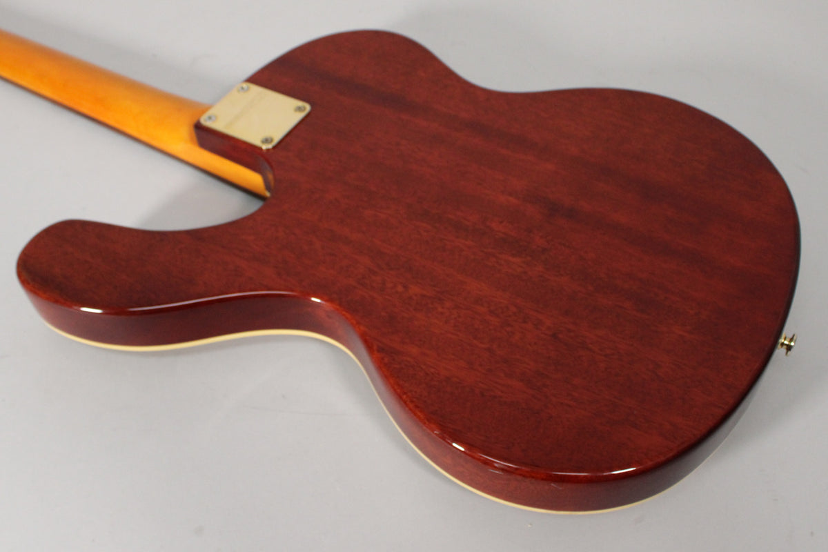 The guitar's back is dark reddish-brown with visible wood grain, cream binding, a gold neck plate, and a gold strap button.